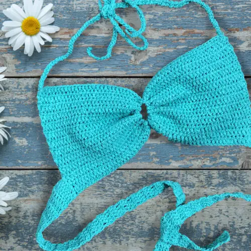 Daisy flowers and crochet bralette on old wooden background