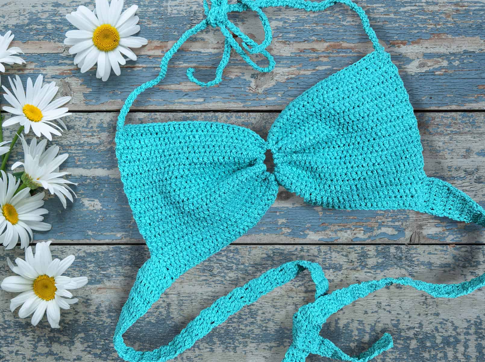 Daisy flowers and crochet bralette on old wooden background