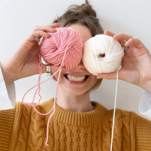 lady holding pink and white yarn smiling