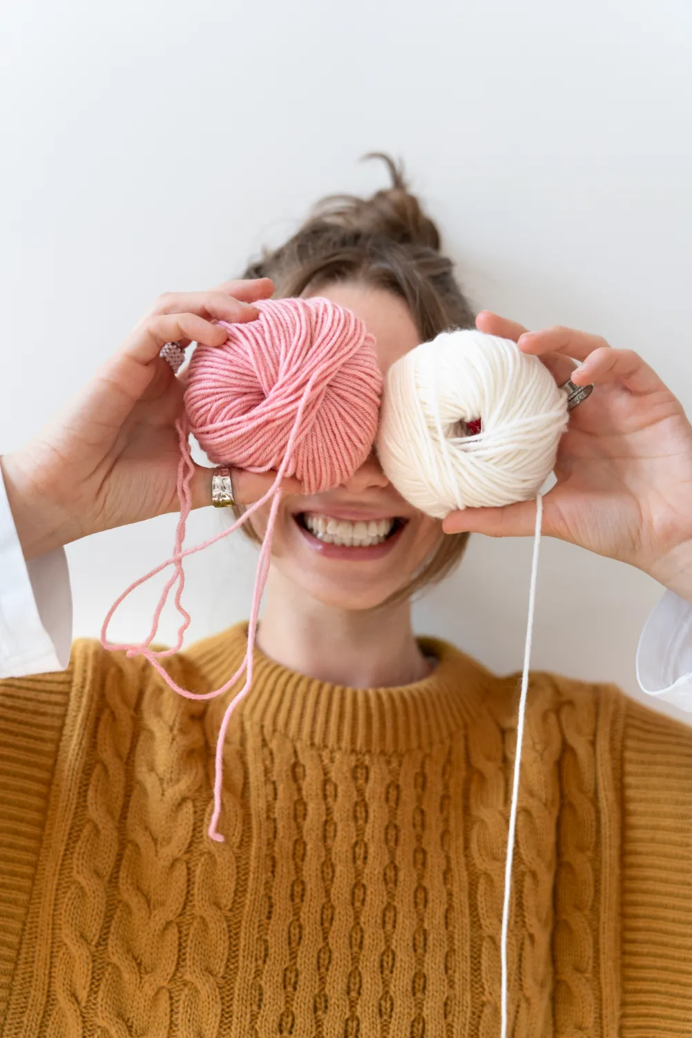 lady holding pink and white yarn smiling