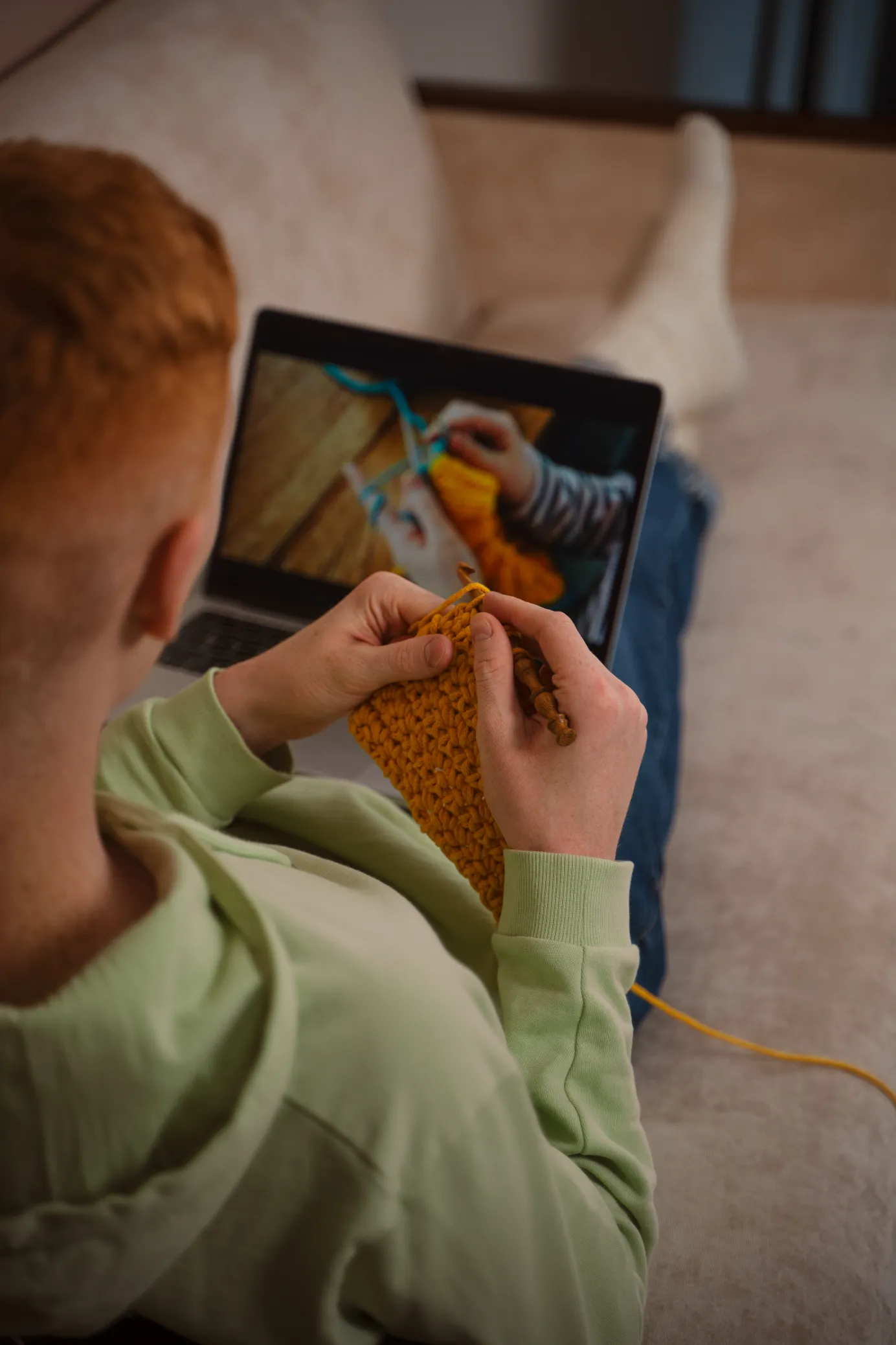 young-man-crocheting and watching a tutorial